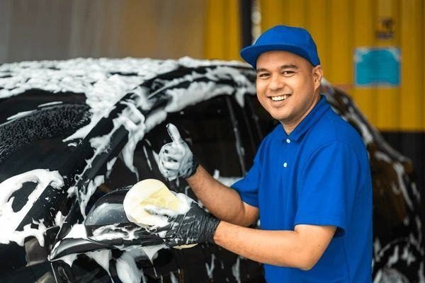 Smiling LIFT attendant giving a thumbs up while washing a car